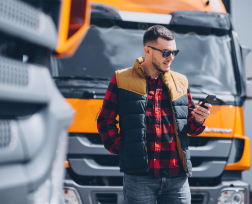 Camionero consultando en su móvil qué vehículos deben tener concertado el seguro obligatorio.